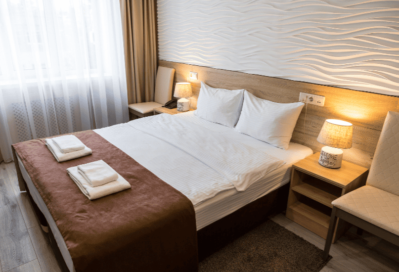 Двуспальная кровать в отеле в Великом Новгороде вид сбока.png